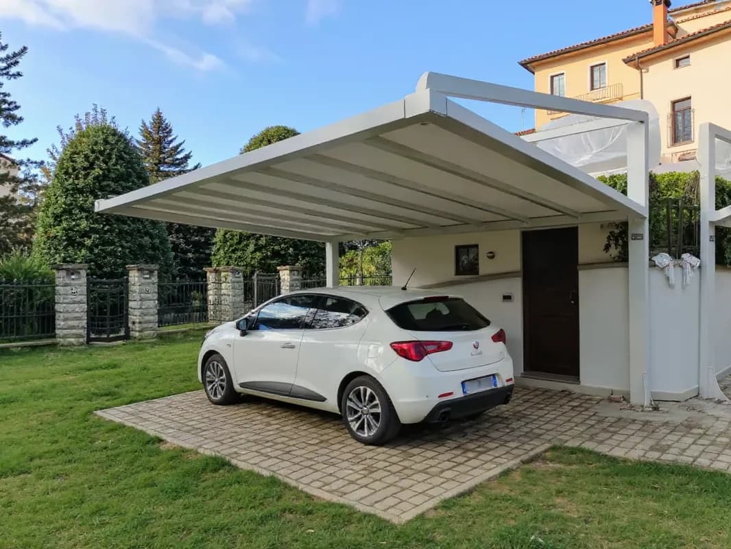 Carport pergolato in acciaio con copertura in PVC accanto a una casa